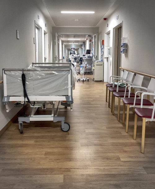 Blick in einen Krankenhausflur auf dem Betten und Geräte stehen, aber keine Menschen zu sehen sind.